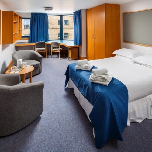 Twin bedroom at Christ’s College, Cambridge, showing a functional accommodation space with two single beds, desks, and chairs in a traditional college setting.