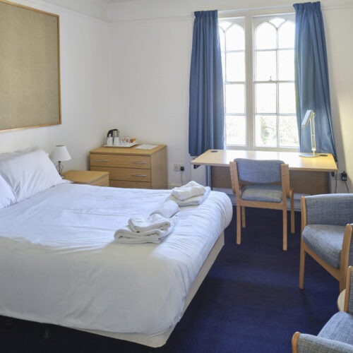 Superior double room ensuite with bed, desk and chairs at Christ's College Cambridge as well as a garden view.