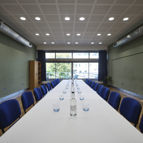 JCR meeting room space at Christ's College, Cambridge set up in a boardroom style with glasses and water and a view of the window. A versatile boardroom space in Cambridge