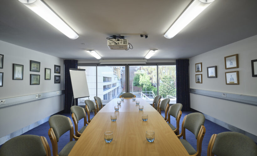 New Court Seminar Room set up in boardroom style with a flipchart and garden view to parts of the Darwin Garden.
