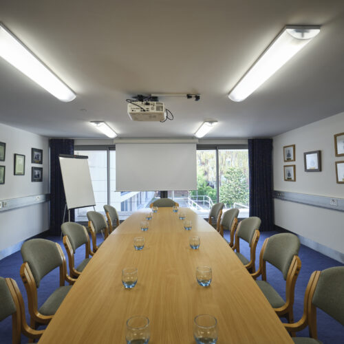 New Court Seminar Room set up in boardroom style with a flipchart and garden view to parts of the Darwin Garden. An ideal seminar room in Cambridge.