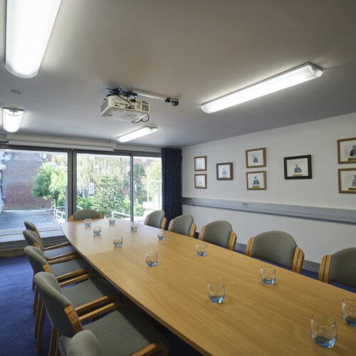 New Court Seminar Room set up in boardroom style with a flipchart and garden view to parts of the Darwin Garden. An ideal seminar room in Cambridge.