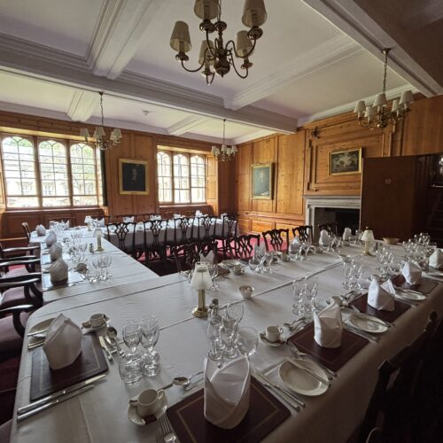 Christ's College Old Combination Room set up for dinner with tableclothes, cutlery, plates and glasses.