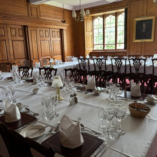 Christ's College Old Combination Room set up for dinner with tableclothes, cutlery, plates and glasses.