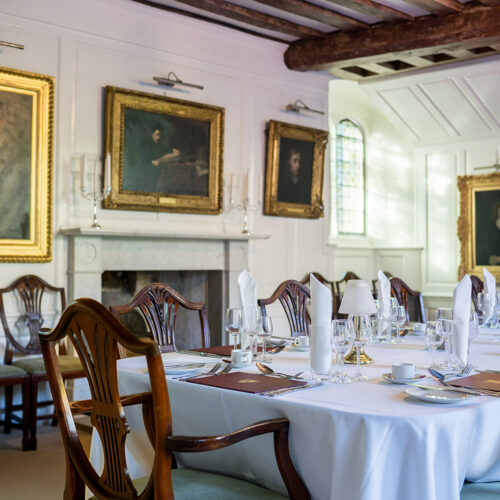 Interior of the Portrait Room set up for dinner at Christ’s College, Cambridge, with rows of framed academic portraits in a formal, historic setting.