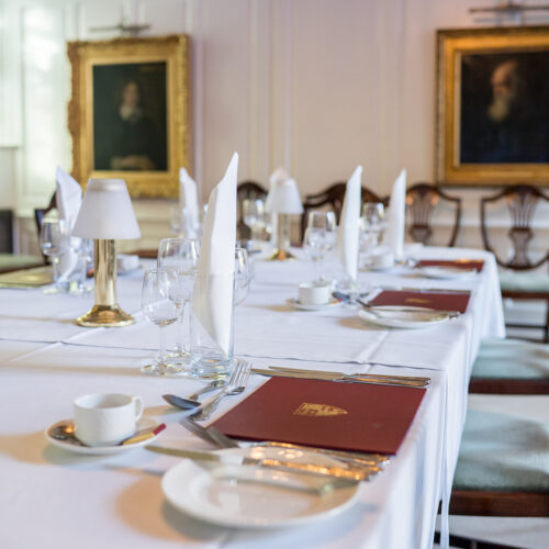 The Portrait Room set up for dinner at Christ’s College, Cambridge, featuring historic framed portraits displayed along traditional panelled walls.