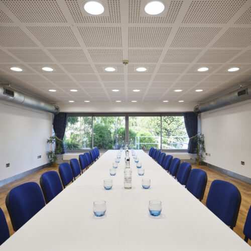 TV Meeting Room set up in boardroom style with glasses and water and a view of the Darwin Garden at Christ's College. A small meeting room in Cambridge