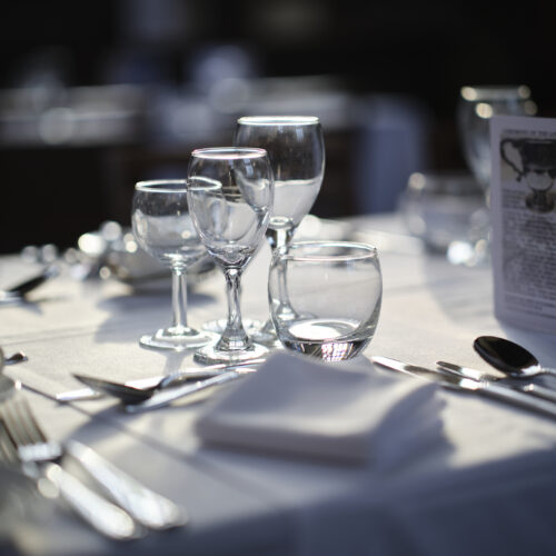 A table in the Great Hall at Christ's College set up for private dining in Cambridge. The table is set up with white linen and cutlery.