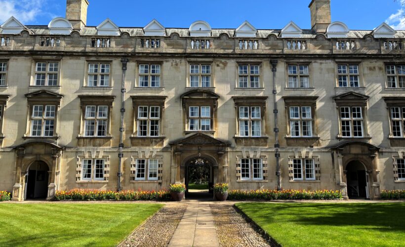 Christ's College Second Court with a lush green lawn and a border of beautiful orange and yellow tulips.